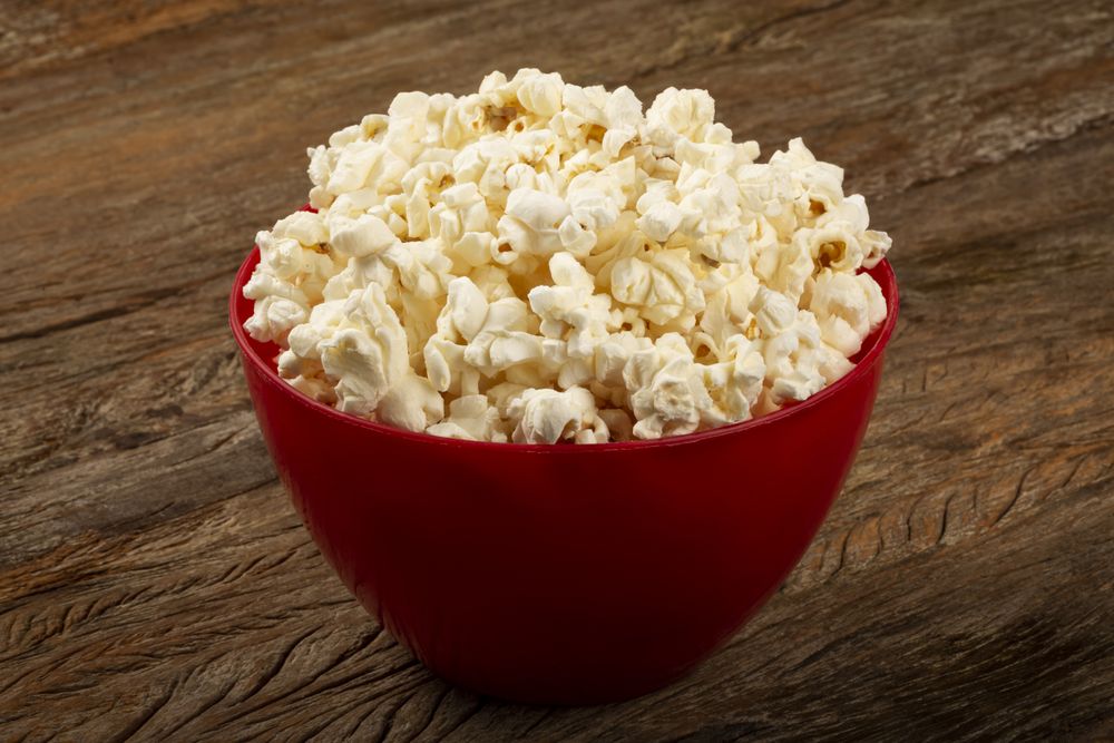 Bowl with salted popcorn sore the table.