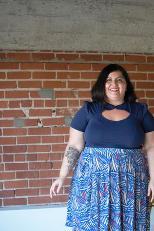 Woman with tattoos smiling in front of a brick wall