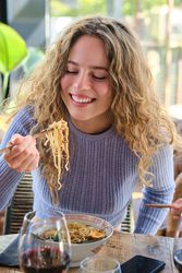 Smiling woman eating delicious noodles
