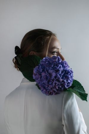 Back view of young woman with Hortensia flower against gray background