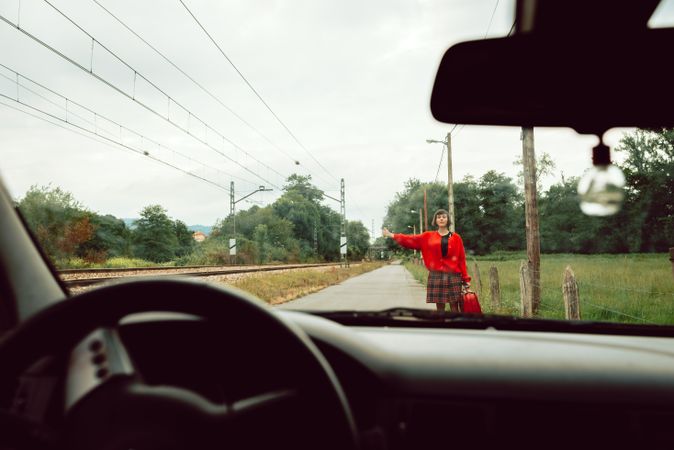 Woman in red sweater catching car on road
