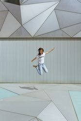 Cheerful woman jumping near modern wall