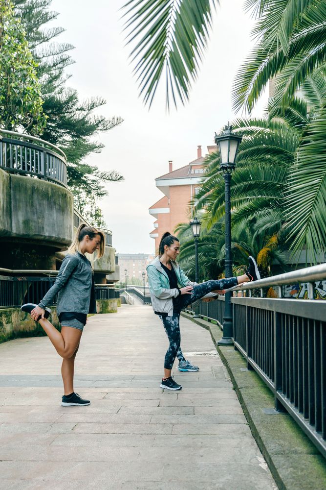 Women runners stretching legs before training