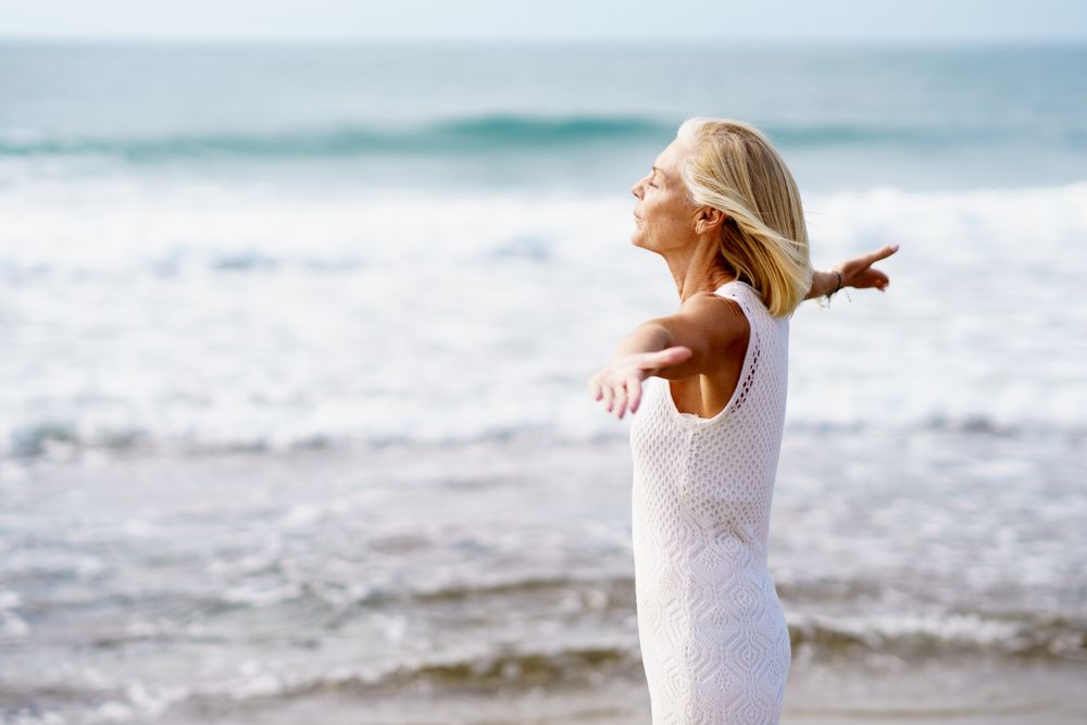 Older woman with outstretched arms on the coast