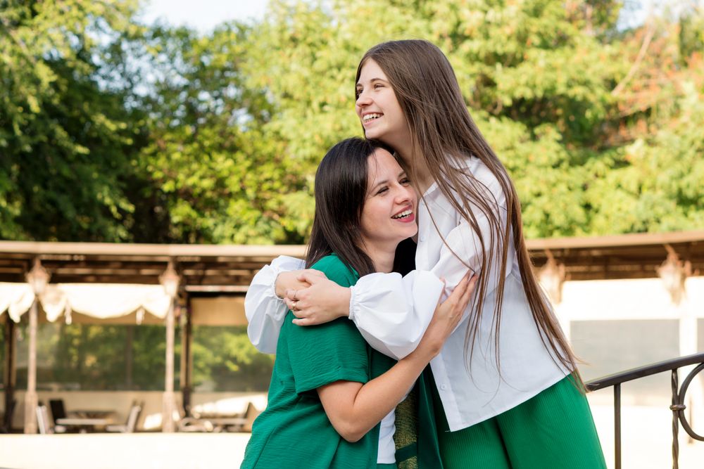 Mom and teenage daughter hugging on walk in park