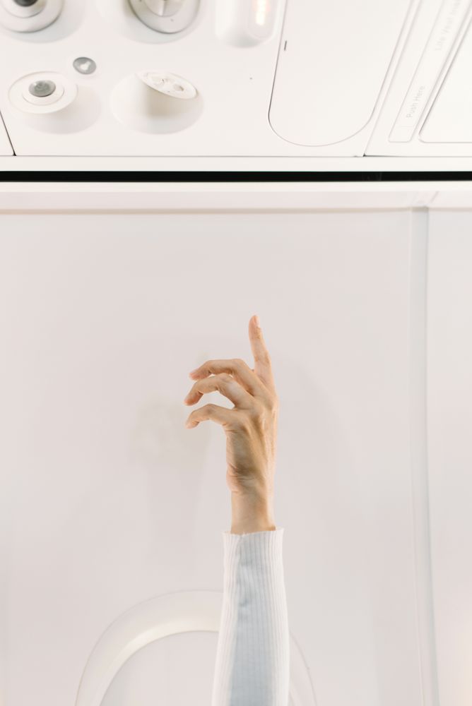 Person in white sweater raising hand up in plane