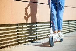 Front of female in jeans riding scooter