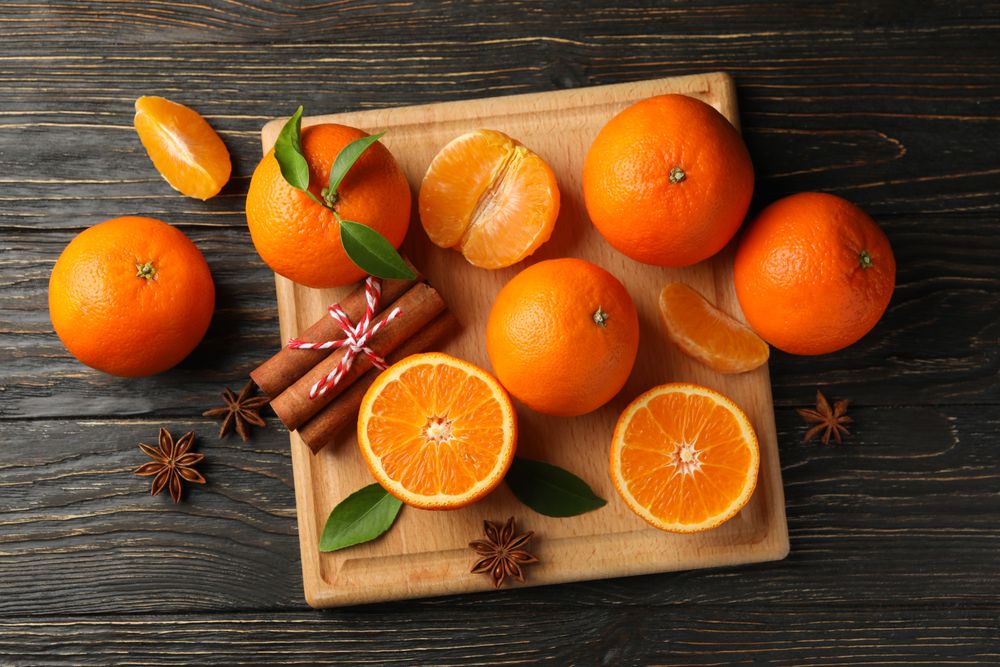 Board with mandarins and cinnamon on wooden background