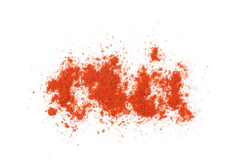 Loose dark red spice sprinkled on blank background