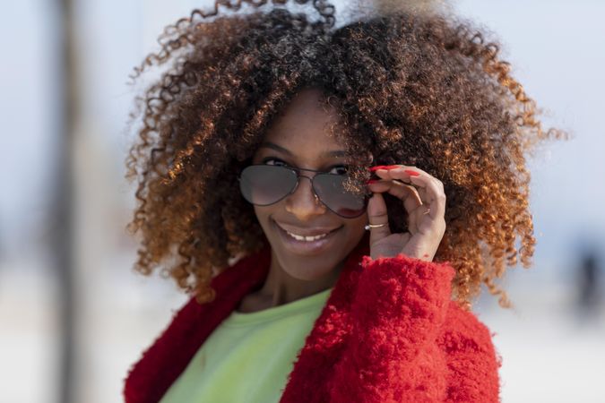 Smiling female with hand to her sunglasses on sunny day
