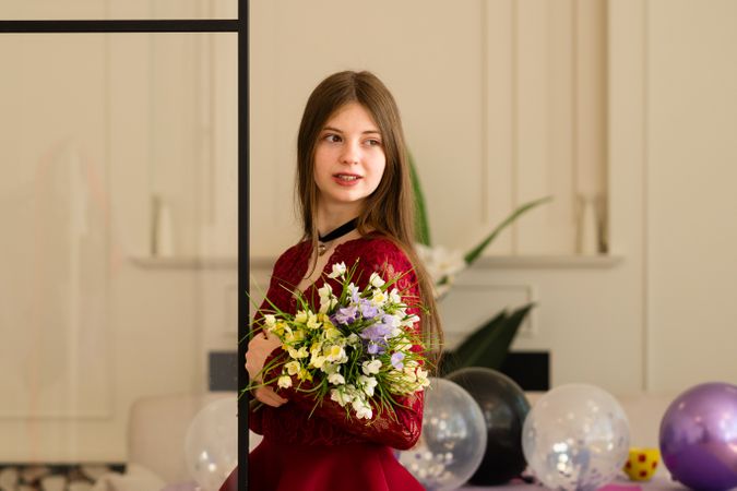 Teen girl in red lace dress holding bouquet of flowers