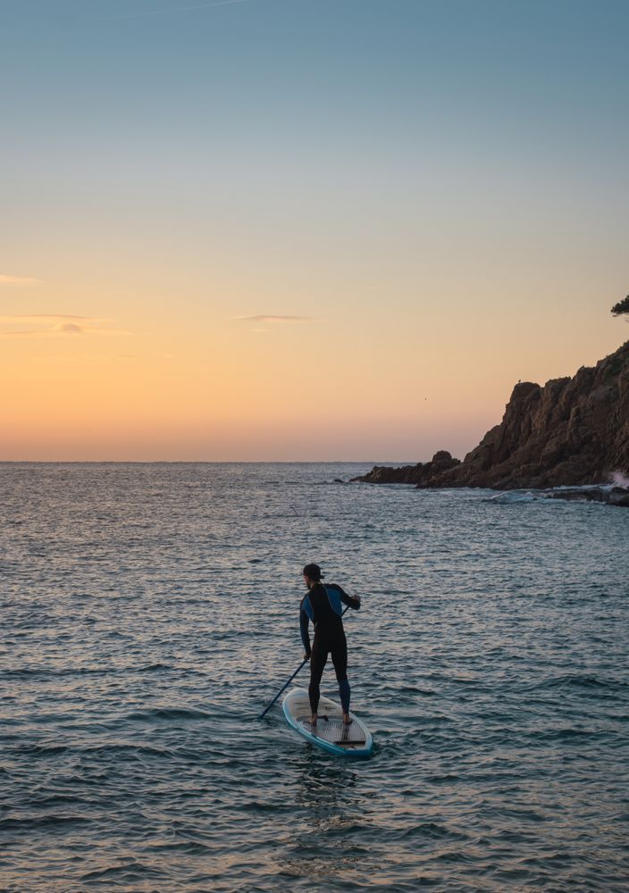 Man practicing paddle surfing with neoprene in a sunrise