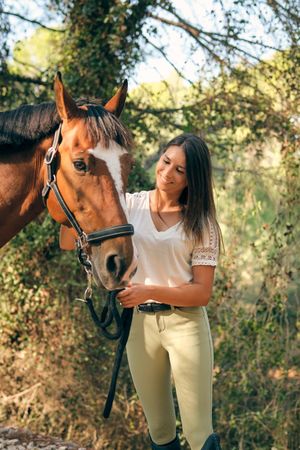 Happy horsewoman with horse in forest