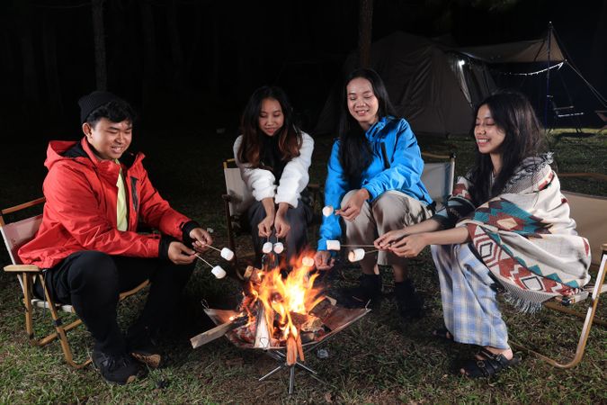 Group of Asian Friends Camping and Making Smores at Campfire