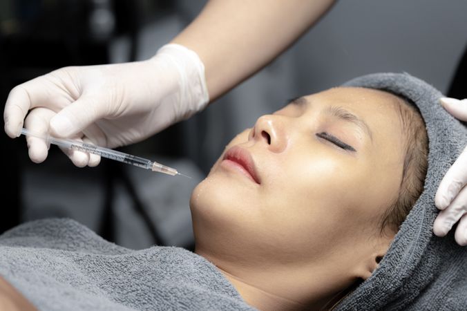 A young woman injects vitamins into her face in a beauty clinic.