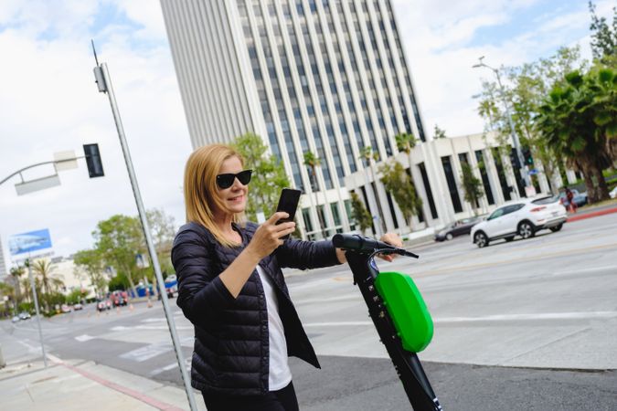 Woman browsing smartphone and riding electric scooter