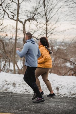 Black man and woman jogging outdoor during winter