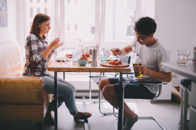 Young woman and man sitting at a breakfast table eating