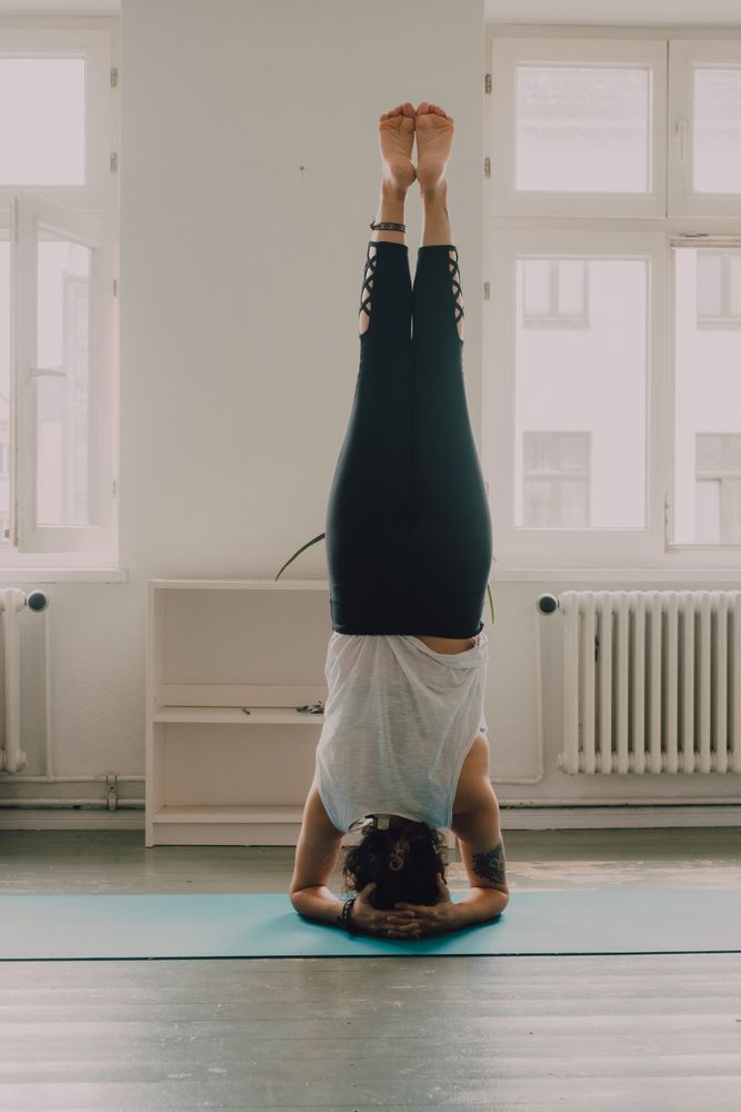 Fit woman practicing yoga pose and standing on head at home