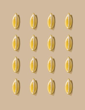 Pattern of lemon fruit slices and pastel sand background