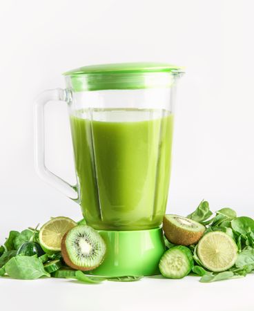 Blender with green smoothie with ingredients:  kiwi, cucumber, lime and spinach