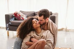 Multiethnic couple hugging on floor at home