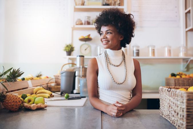 Woman standing behind counter looking away and smiling