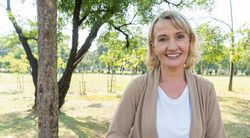 Mature blonde woman standing outside in tree filled park
