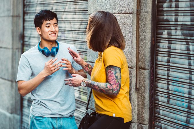 Joyful multiracial friends talking while standing on city street