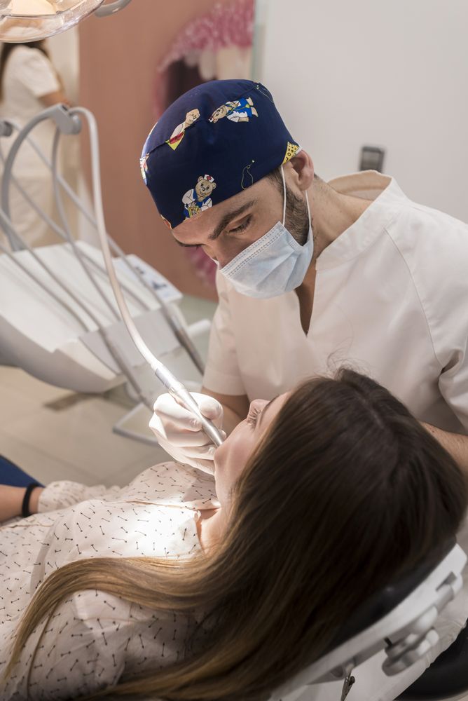 Male dentist drilling tooth in female teenage patient