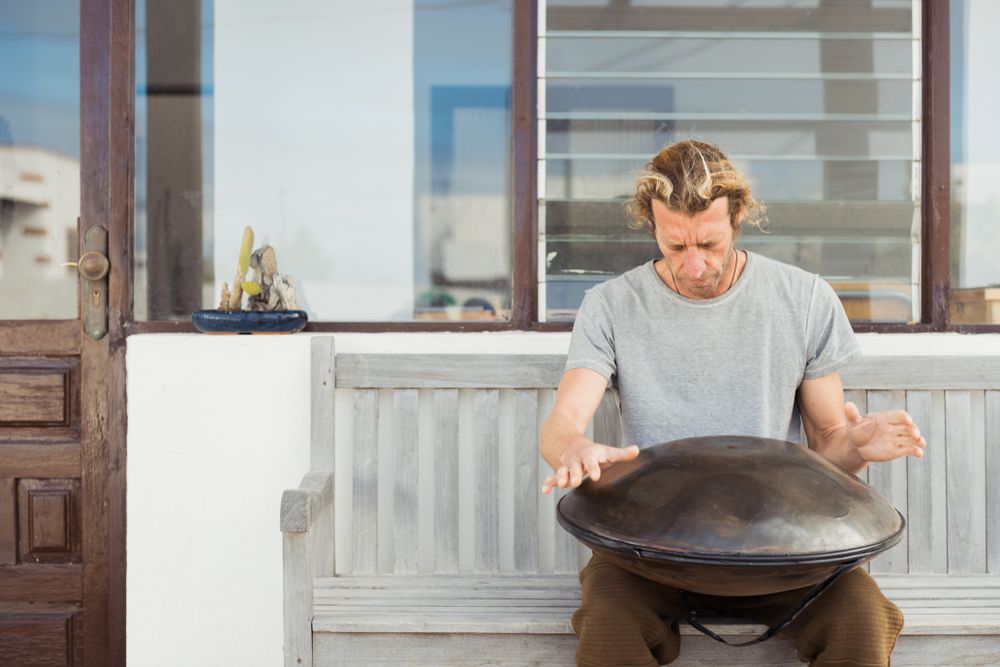 Blond man sitting on bench with big hand drum