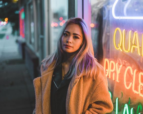 Woman with colored hair standing near colorful neon signage