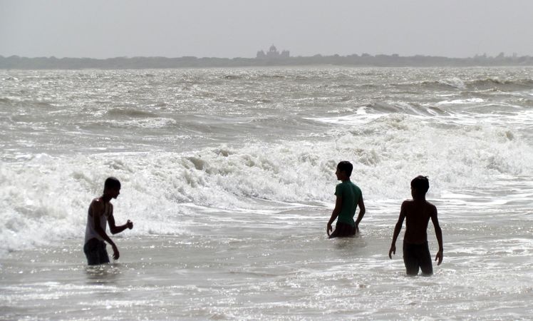 Teenage boys wading in sea waves
