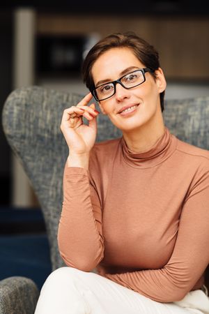 Portrait of woman with short hair and eyeglasses sitting in smart casual