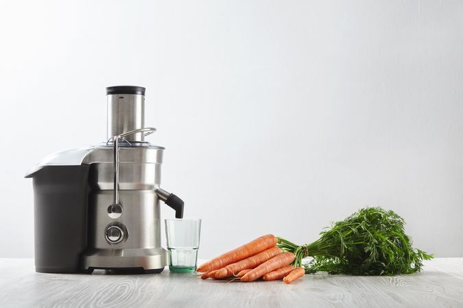 Silver juicer with bunch of carrots