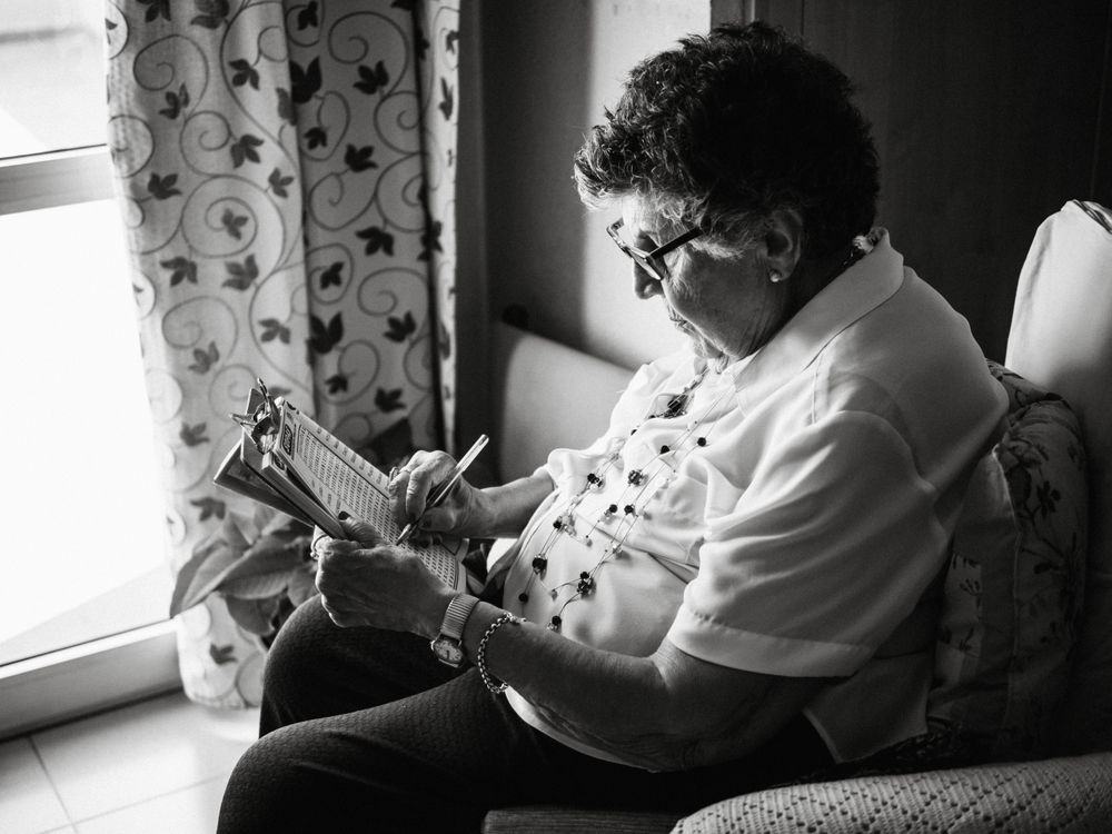 Mature woman solving crosswords in apartment