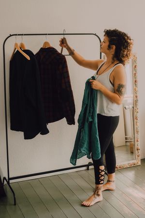 Happy woman hanging clothing on clothes rail at home