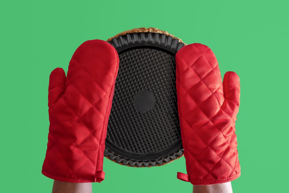 Bottom view of person wearing oven mitts and holding a pie dish