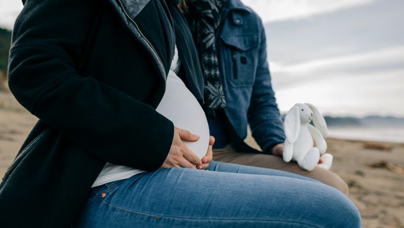 Pregnant person on the beach with her partner