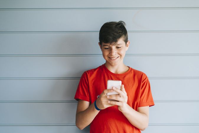 Profile of a smiling male teen texting on a smart phone
