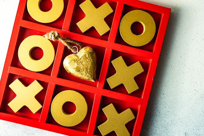 St. Valentine day card concept with golden heart ornament in center of tic-tac-toe game