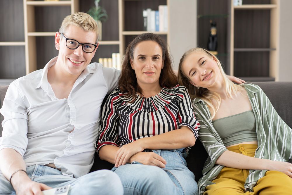Portrait of happy family sitting on couch in the living room smiling and looking at camera