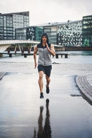 Male jogging on wet concrete on overcast day