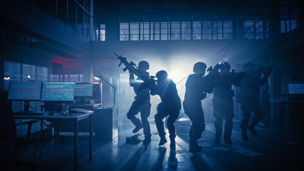 Masked Squad of Armed SWAT Police Officers Storm a Dark Seized Office Building with Desks and Computers.