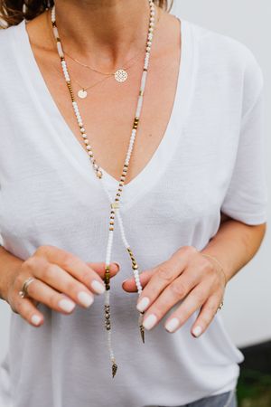 Cropped image of woman wearing light shirt and beaded necklace