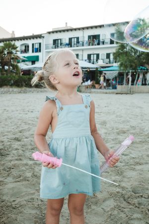 Funny curious girl blowing soap bubbles and entertaining on summ