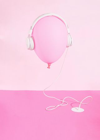 Pink balloon wearing headphones plugged into pink desk