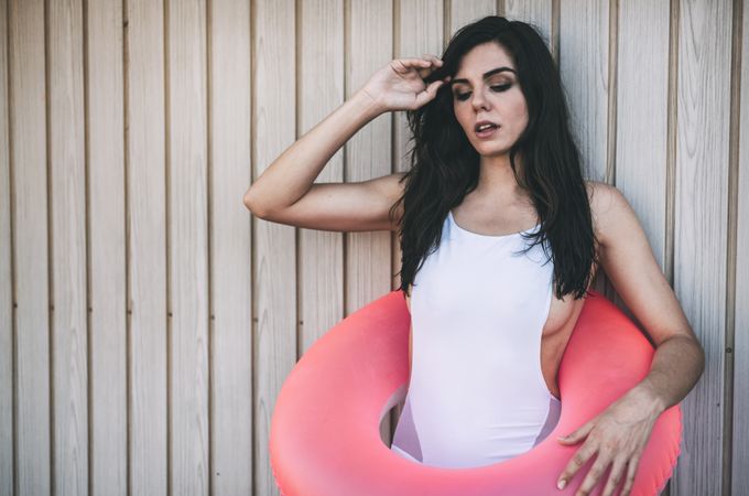 Woman with a swimming ring posing by white wooden fence