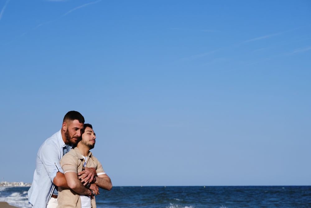 Gay couple hugging on seaside