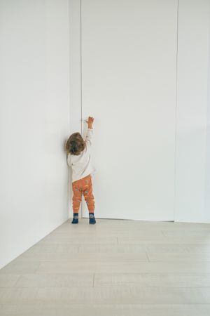 Unrecognizable toddler reaching for doorknob at home